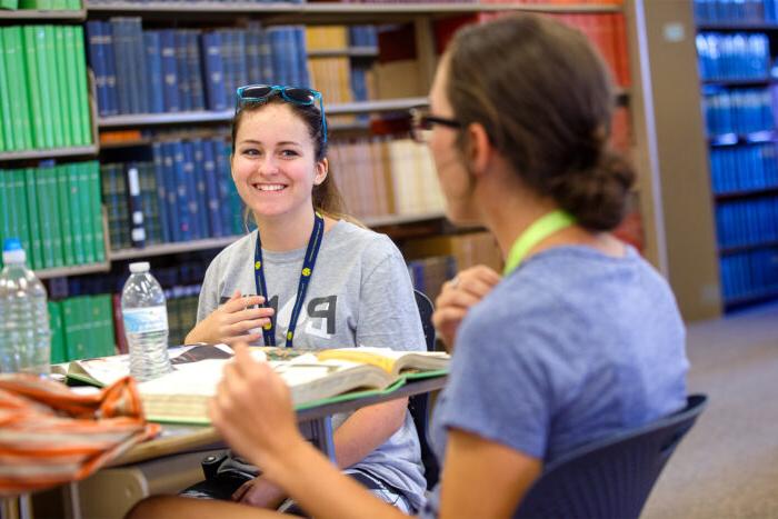 Two student happily studying in a library.